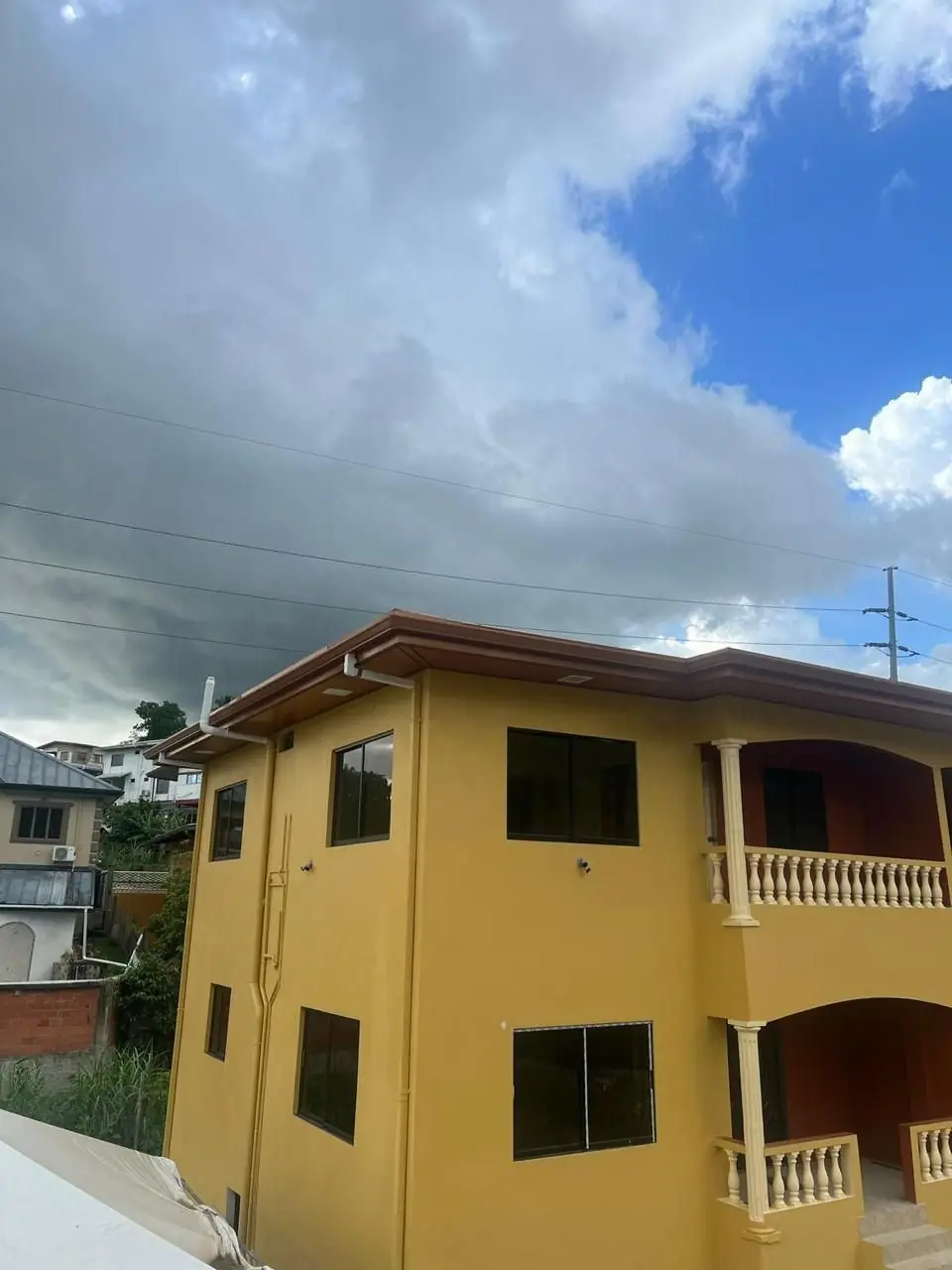 Yellow two-storey townhouse exterior with balcony
